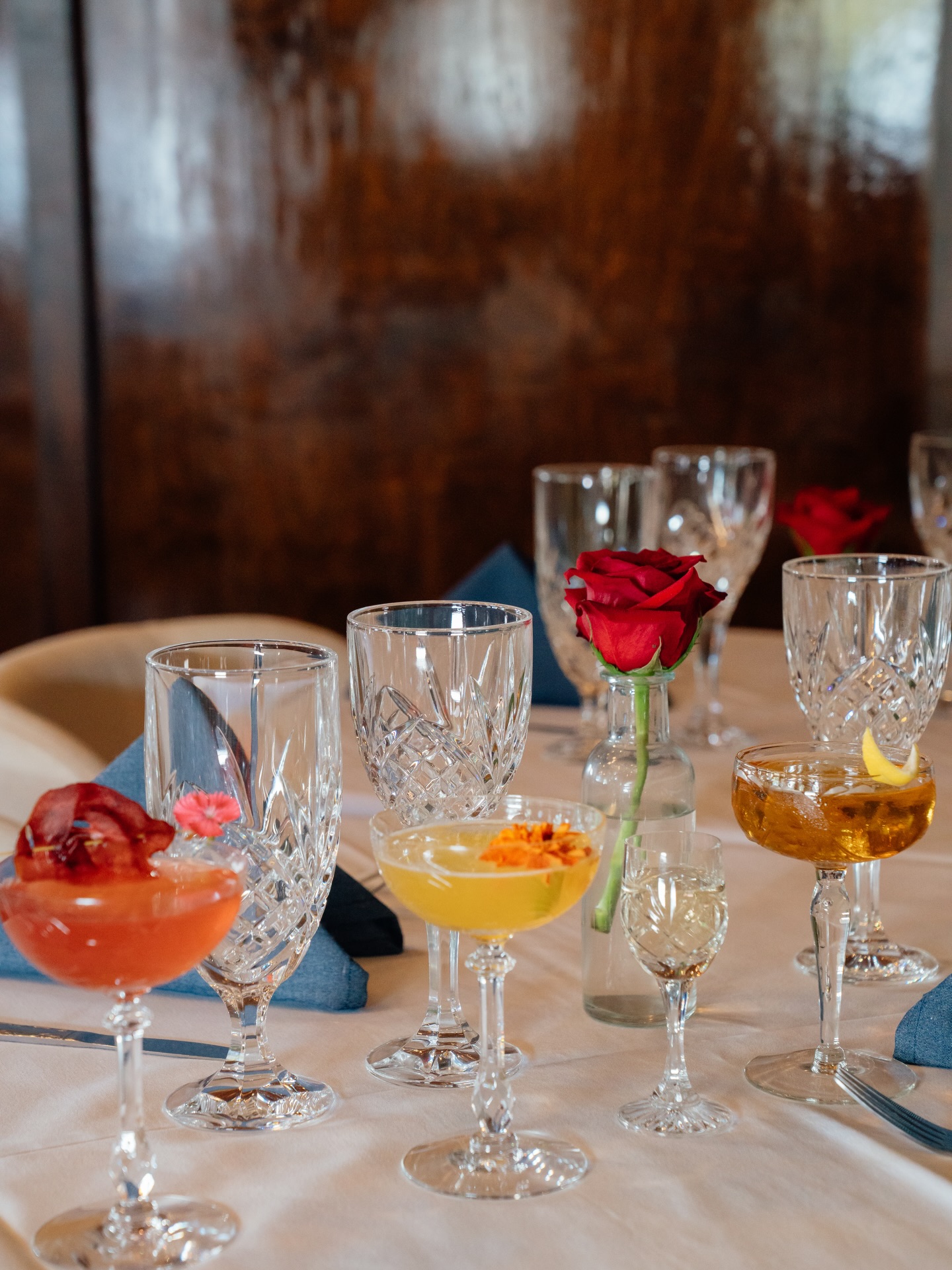 Cocktails and crystal on a laid table with a red rose