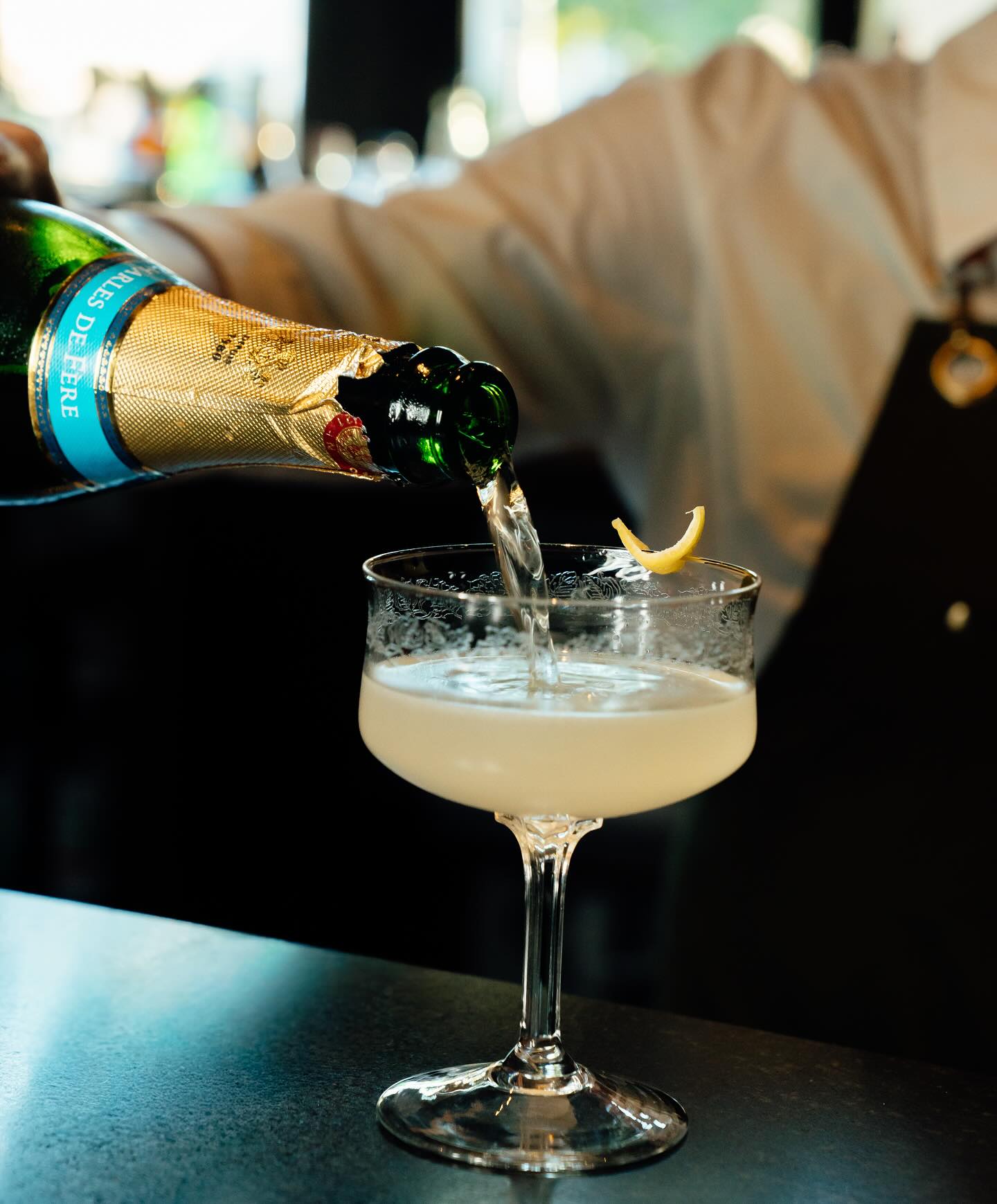 Champagne poured into a cut glass coupe at the bar