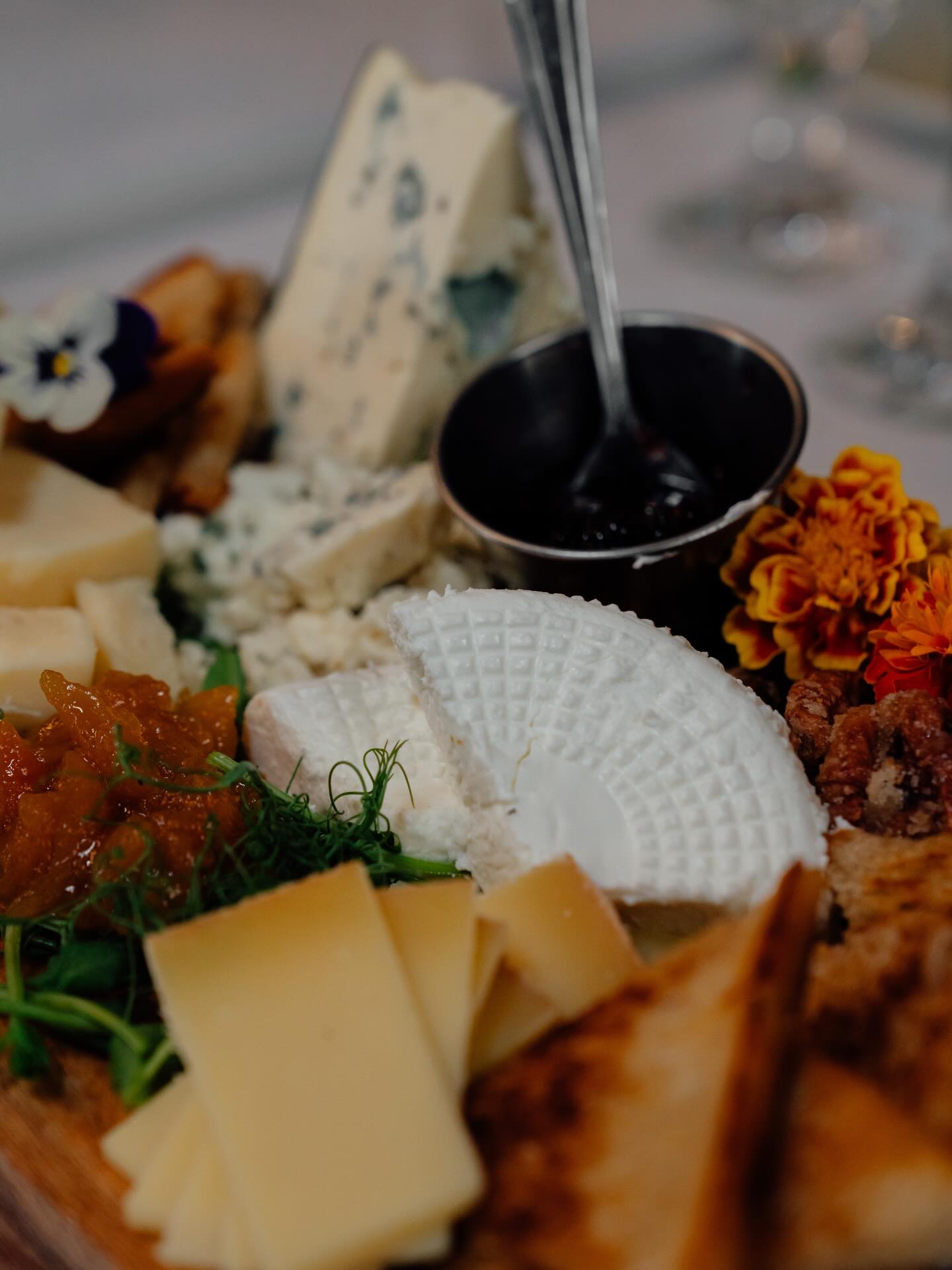 A cheese board with fruit, honey and marigold petals