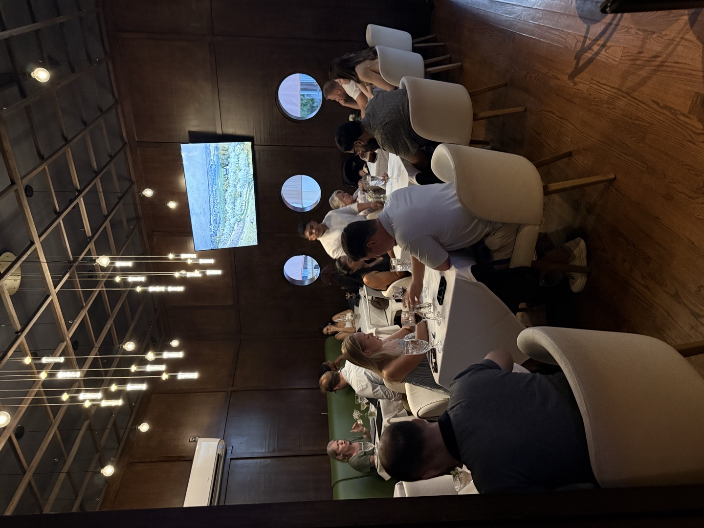 Guests at white-clothed tables in the panelled dining room, lights overhead